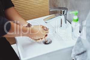 The best defence against germs. an unrecognisable man washing his hands in the bathroom sink.
