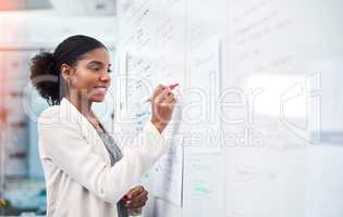 Project manager writing on a whiteboard to plan ideas and visualize business strategy. Focused, confident and thoughtful businesswoman showing ambition and dedication while working in an office