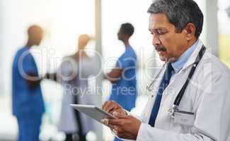 Doctor with tablet reading test results, browsing treatment options and researching medicine side effect in hospital. Mature medical professional and healthcare worker planning schedule on technology