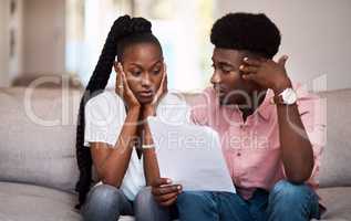 Well have to take out another loan. a young couple looking stressed while going over paperwork at home.
