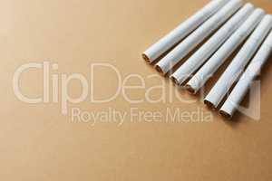 Did someone say smoke break. Studio shot of a row of cigarettes against a brown background.