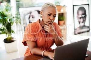 Putting her thought and action into achieving results. a young businesswoman looking thoughtful while working on a laptop in an office.