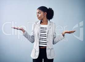 Female thinking about a business option or choice for a decision between offers. Confused, anxious female shrugging, doing balance hand gesture with a grey copyspace background.
