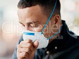 Its so much more than just a cough these days. a young man coughing and wearing a mask against a city background.