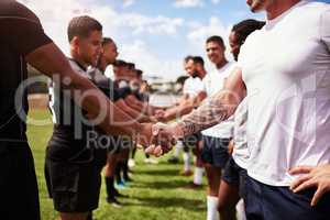 Play well, play fair. a group of young rugby players shaking hands on the field.