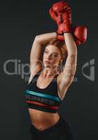 The sooner you start being fearless, the better. Studio shot of a sporty young woman wearing boxing gloves against a black background.