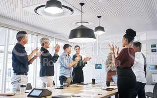 Outstanding achievements all round. a group of businesspeople clapping during a meeting in a modern office.