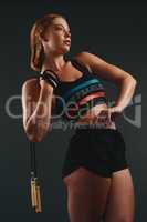 Building stamina, every skip of the way. Studio shot of a sporty young woman posing with a skipping rope against a black background.