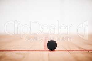 Ill be bouncing around in no time. a squash ball on the floor of a squash court.