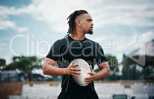 Rugby is his profession. a handsome young rugby player holding a rugby ball while standing on the field.