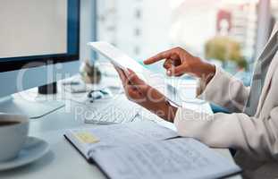 Businessperson hands working on a digital tablet at a desk in a modern office. Closeup of business professional multitasking documents or checking data, schedule and daily plan at the workplace.