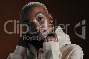 Id call my style cool and comfy. Studio portrait of an attractive young woman wearing a hoodie and posing against a brown background.