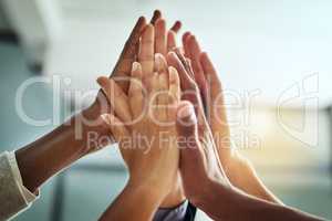 Hands, huddle and high five while a group of diverse businesspeople celebrate and motivate each other at the workplace. Colleagues winning and achieving success through teamwork and collaboration