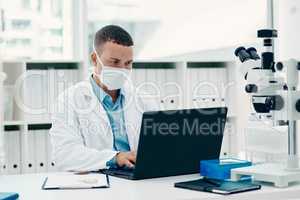 Time is ticking to find a cure. a young scientist using a laptop while working on a coronavirus cure in a laboratory.