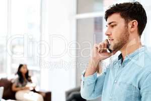 Handling business matters over the phone. a young businessman talking on a cellphone in an office.