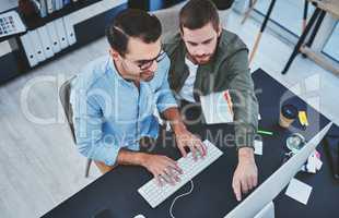 Working together with cohesion. two young designers working together on a computer in an office.