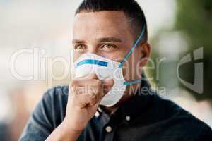 When a cough could turn into something more serious. a young man coughing and wearing a mask against a city background.