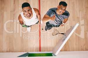 All you need to bring is your team spirit. High angle shot of two young men showing thumbs up at a squash court.