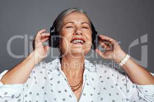 I guarantee you that music will make you feel better. Studio shot of a senior woman wearing headphones while listening to music against a grey background.