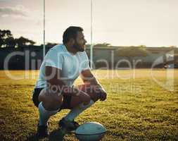 The field is home. Full length shot of a handsome young rugby player crouching on the field during the day.