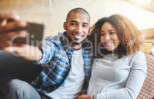 Smiling couple taking selfie photo on phone together for memories of a romantic relationship while looking relaxed at home. A young trendy dating boyfriend and girlfriend taking a portrait picture