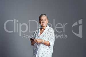 Technology makes life so convenient and Im all about convenience. Studio shot of a senior woman using her cellphone while standing against a grey background.