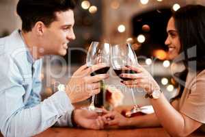 Lets drink to a beautiful evening. a married couple sharing a toast over a romantic dinner.