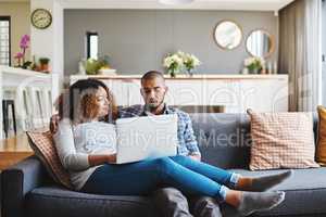 A relaxed couple on sofa watching movie on laptop or browsing internet for a romantic afternoon indoors. Casual, young and in love boyfriend and girlfriend bonding while searching the web on laptop
