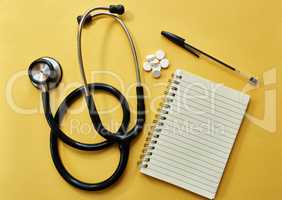 Just what the doctor prescribed. Studio shot of a stethoscope, notepad, pen and pills against a yellow background.