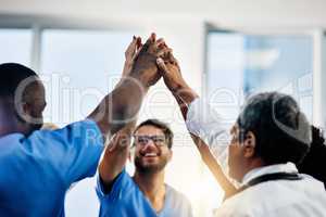 Doctors celebrating medical success after working together as a team and give each other motivating a high five as a group in a hospital. Healthcare workers joining hands in a huddle showing teamwork