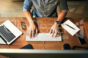 Busy businessman typing on computer keyboard with hands late at night while working, planning and checking email at an office desk job. Productive corporate worker using latest technology