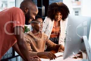 Were using the right platform to get our work out there. a group of businesspeople looking at something on a computer screen in an office.