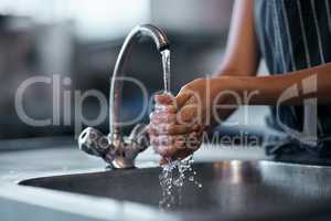 The health inspector would be very proud. a woman washing her hands in the sink of a commercial kitchen.