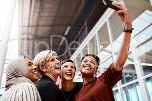 You can just tell that they have the utmost confidence. Portrait of a group of businesswomen taking selfies together in an office.