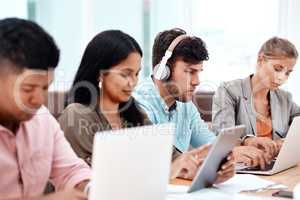 Wireless is the only way to work. a group of young business colleagues sitting in a row at a table in the boardroom.