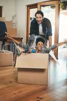 Fun, playful and laughing homeowners playing in box and enjoying new home as real estate investors. Silly interracial couple and happy man pushing woman in living room of purchased property