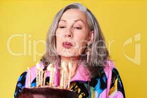 Dont count the years, make the years count. a confident and stylish senior woman holding her birthday cake against a yellow background.