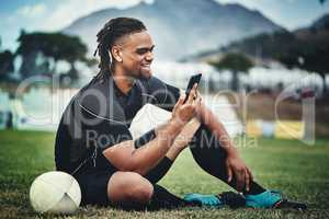 This has to be the funniest rugby meme ever. Full length shot of a handsome young rugby player using a smartphone while sitting in the playing field during the day.