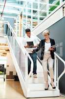 They know precisely which steps to take to reach success. two businesspeople walking down a staircase together in an office.