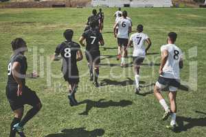 The time has arrived. two focused young rugby teams jogging up onto the field together to start the match outside during the day.