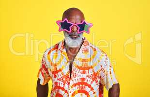 Im always the star attraction. Portrait of a funky and stylish senior man wearing sunglasses posing in studio against a yellow background.