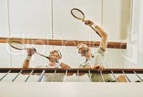 Youll find the winners at the top. two young men watching a game of squash from the viewing gallery.