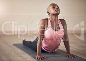 Taking care of my back. an attractive young woman holding an upward facing dog pose during an indoor yoga session alone.