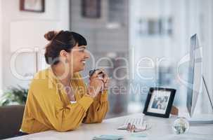 Coffee gets me through my busy day. an attractive young businesswoman sitting in her office and holding a coffee cup while using her computer.