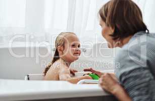 Is the water alright. an adorable little girl bonding with her mother while taking a bath at home.