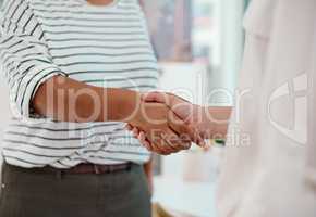 Were partnering up to achieve success. two unrecognizable businesswomen shaking hands together inside an office.
