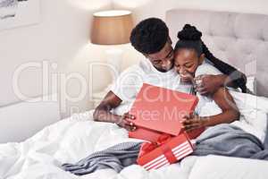 Love is the best gift anyone can ask for. a young man spoiling his girlfriend with gifts in their bedroom.