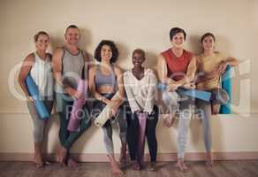 This is the best yoga group. Full length portrait of a diverse group of yogis sitting together and bonding after an indoor yoga session.