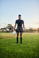 Crushing my sports goals. Full length portrait of a handsome young sportsman standing alone and holding a rugby ball before an early morning practice.