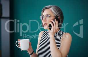 Coffee makes me a better negotiator. a businesswoman having coffee while talking on her cellphone in her office.